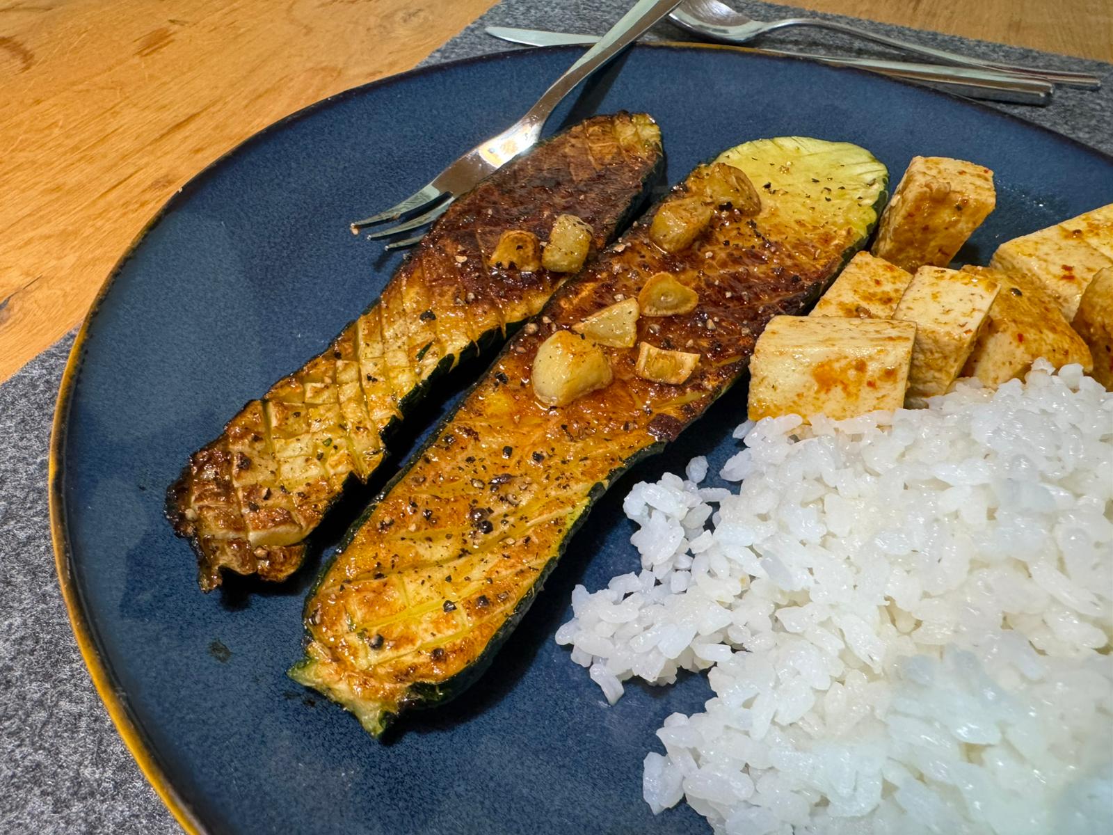 A plate with fried zucchini, tofu and rice